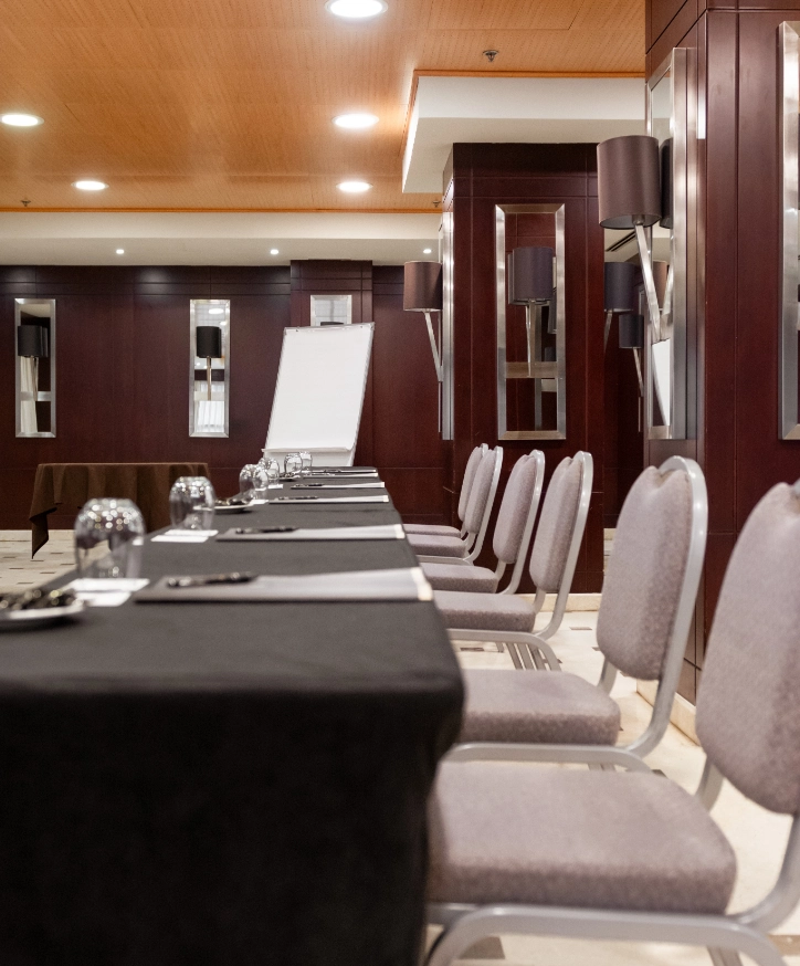 Sala de conferencias con sillas, mesa y pizarra frente a panel de madera.