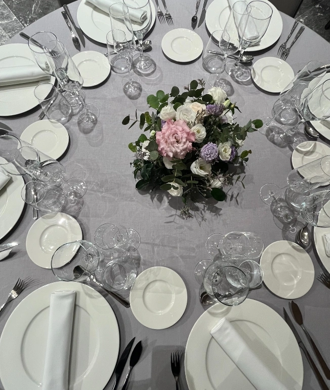 Mesa elegante con platos blancos, copas y centro de flores.