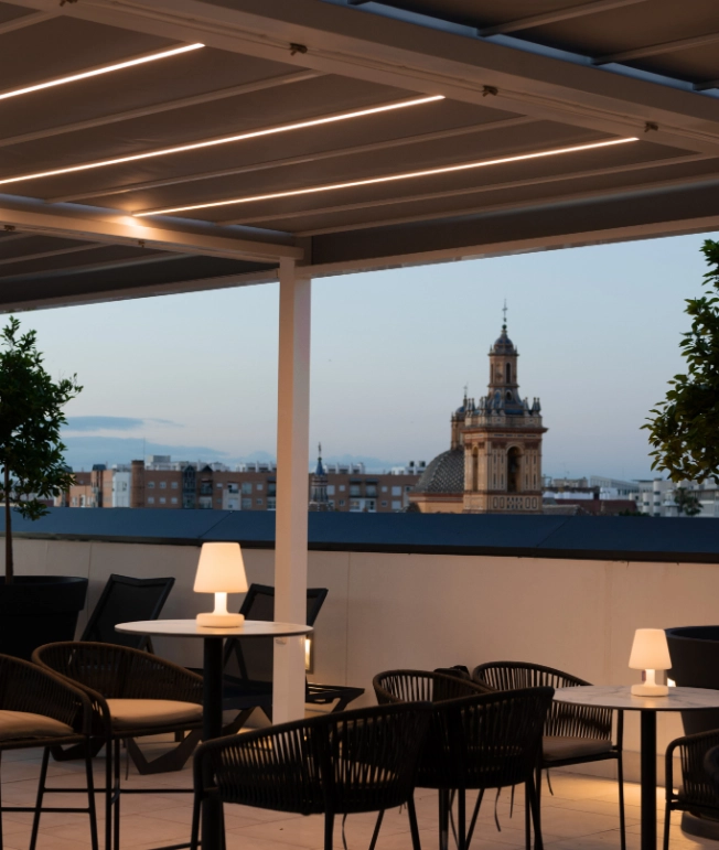 Terraza con mesas y sillas, vista de una c&uacute;pula al atardecer.