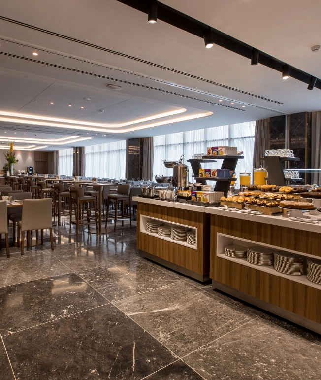 Restaurante buffet con mesas y sillas, alimentos y bebidas en la barra.