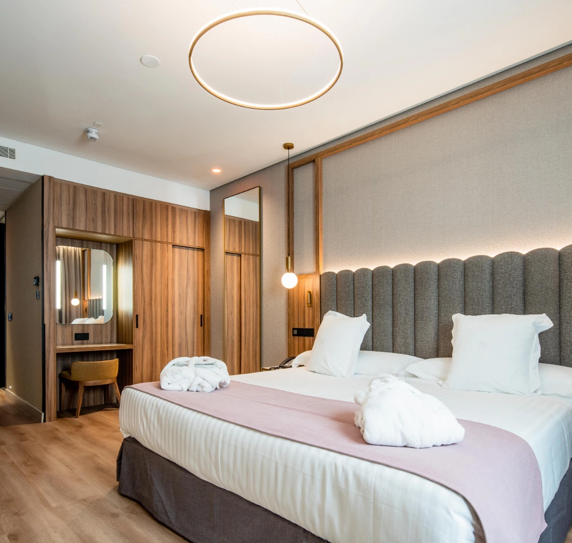 Habitaci&oacute;n de hotel moderna con cama doble y decoraci&oacute;n en tonos neutros.