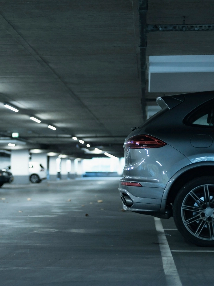 Auto plateado estacionado en un garaje subterr&aacute;neo iluminado.
