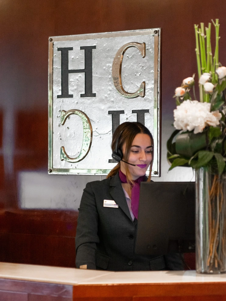 Recepcionista atendiendo frente a una computadora en un hotel.