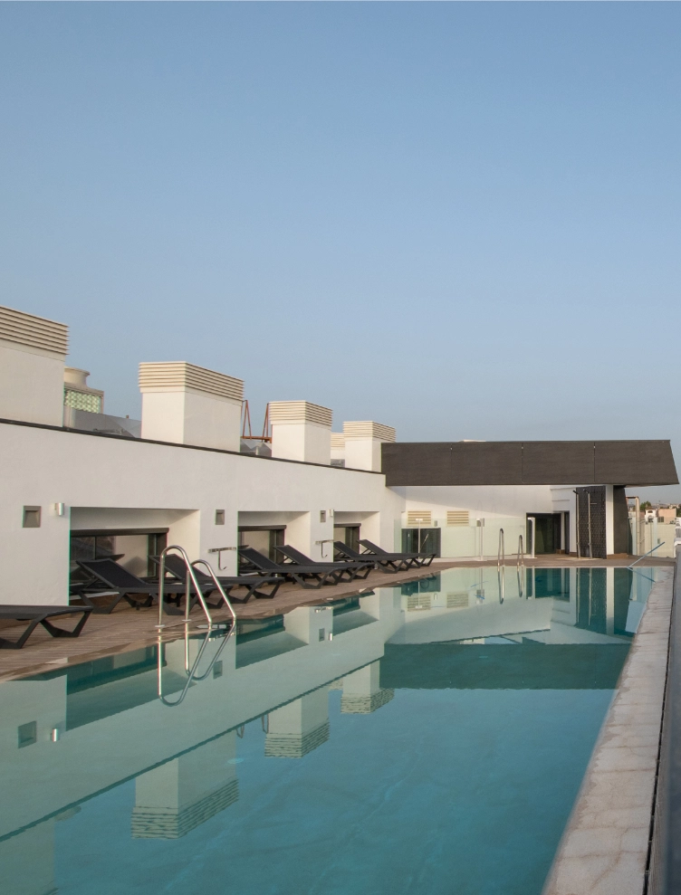 Piscina en la azotea con varias tumbonas y cielo despejado.