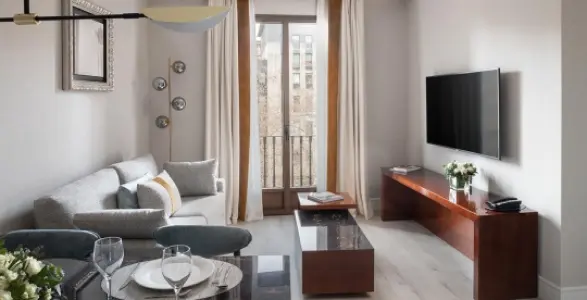 Sala moderna con sof&aacute; gris y televisor en la pared.