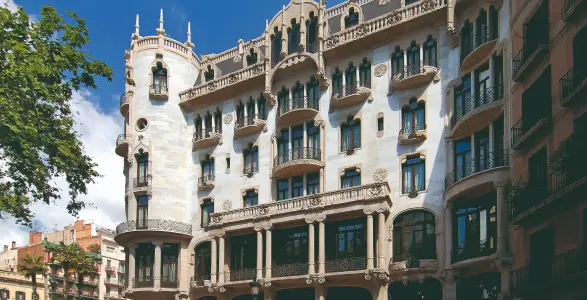 Edificio modernista con balcones elaborados y torre en esquina.