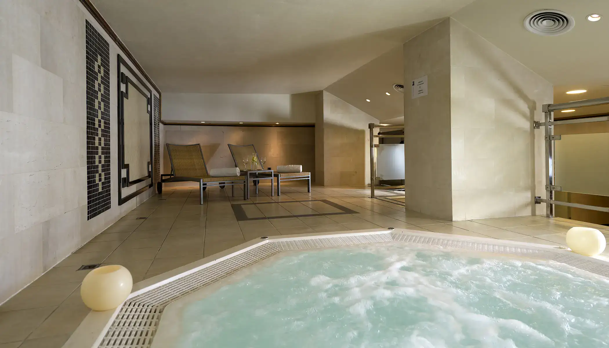 Jacuzzi en spa con camastros de madera y decoraci&oacute;n minimalista.