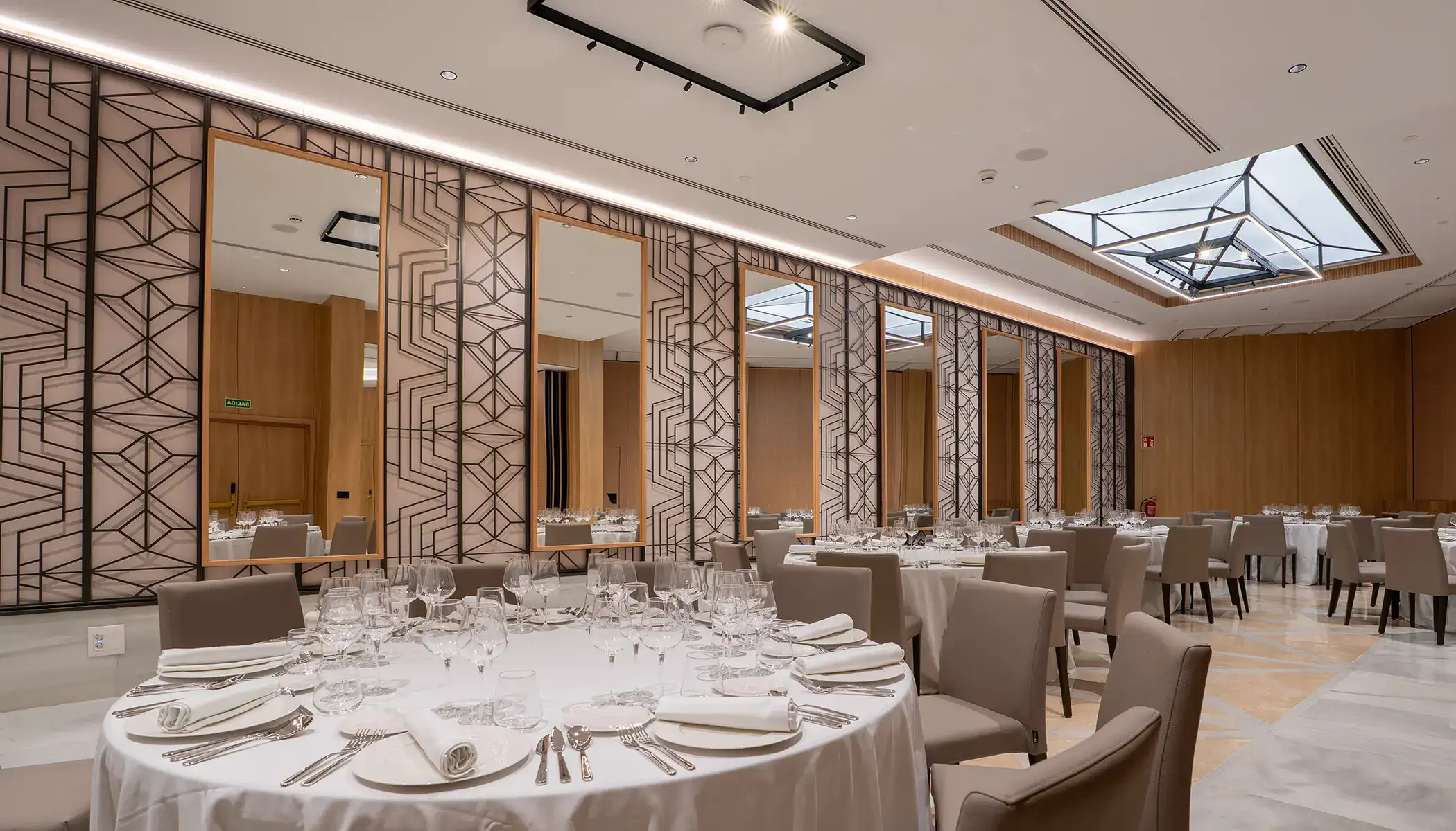 Sal&oacute;n elegante con mesas redondas y decoraci&oacute;n geom&eacute;trica en las paredes.