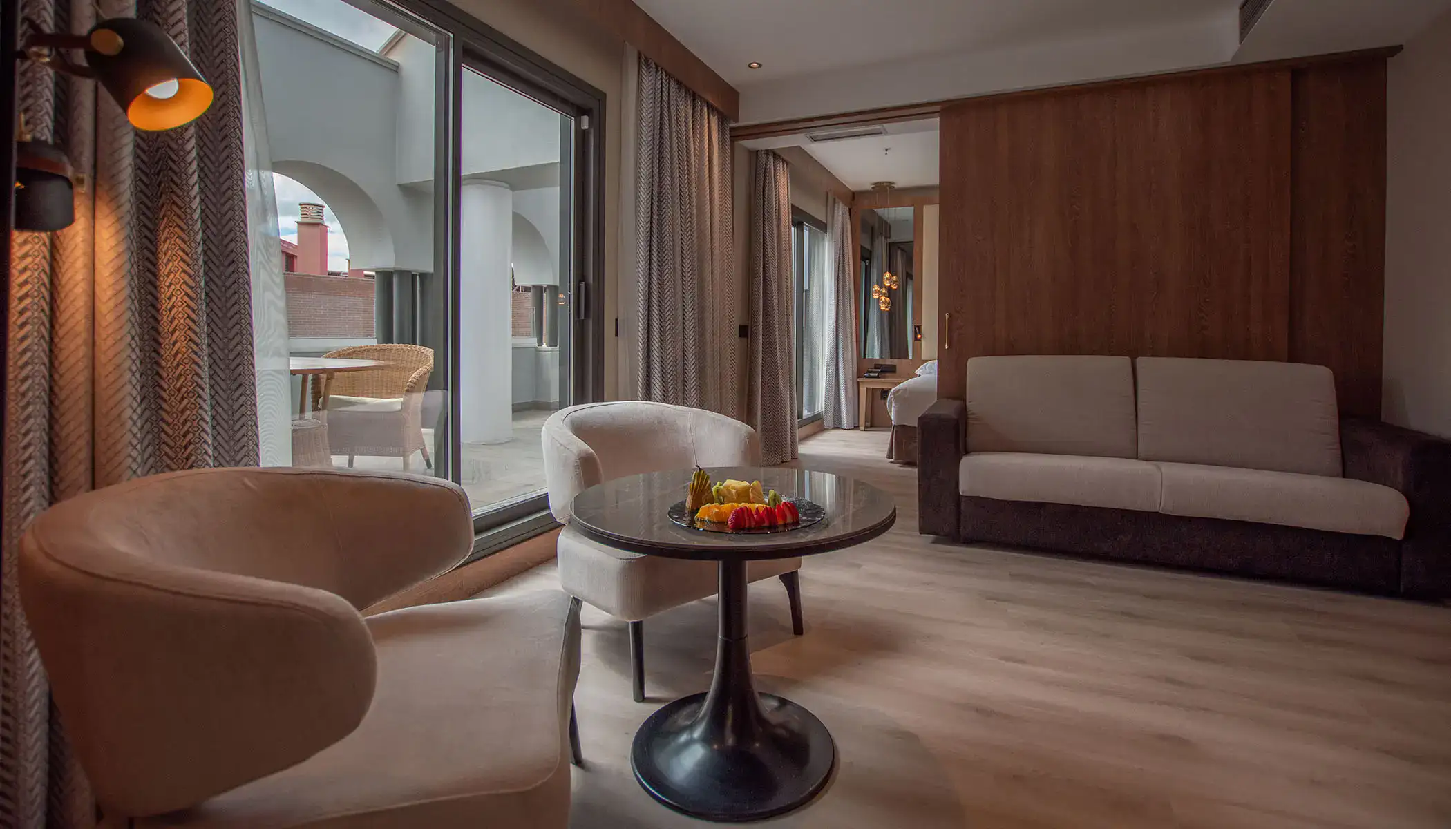 Sala moderna con sillas y mesa, luz c&aacute;lida y puerta a balc&oacute;n.