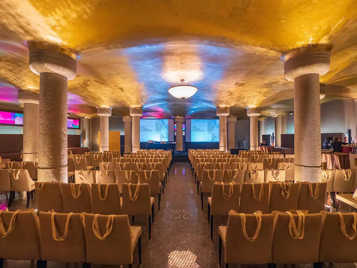 Sala de conferencias vac&iacute;a con sillas y columnas iluminadas de colores.