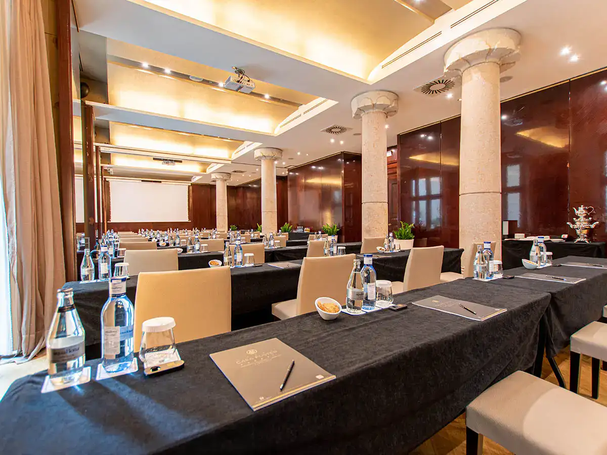 Sala de conferencias con mesas montadas y botellas de agua.