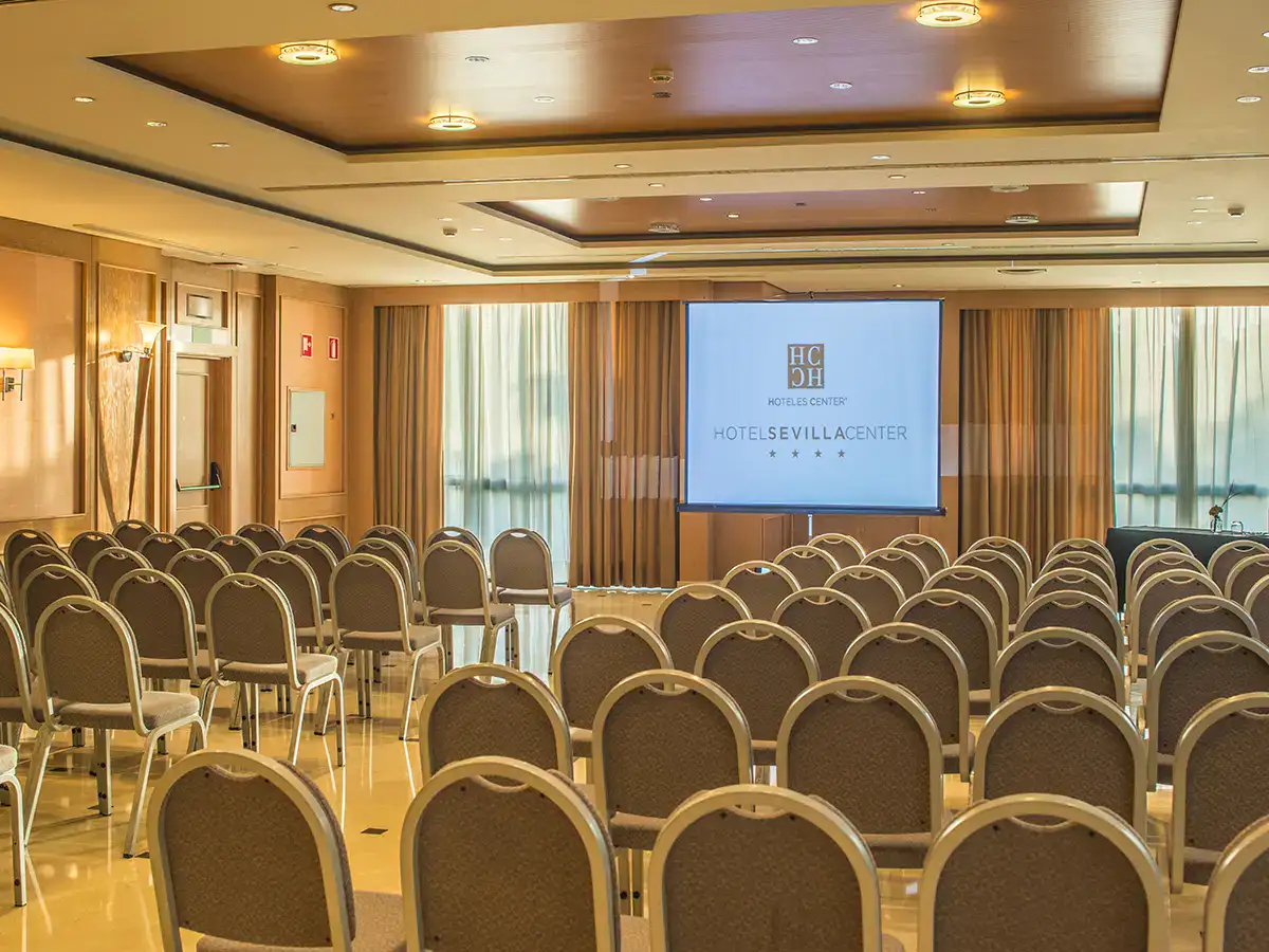Sala de conferencias con sillas y proyector encendido en un hotel.