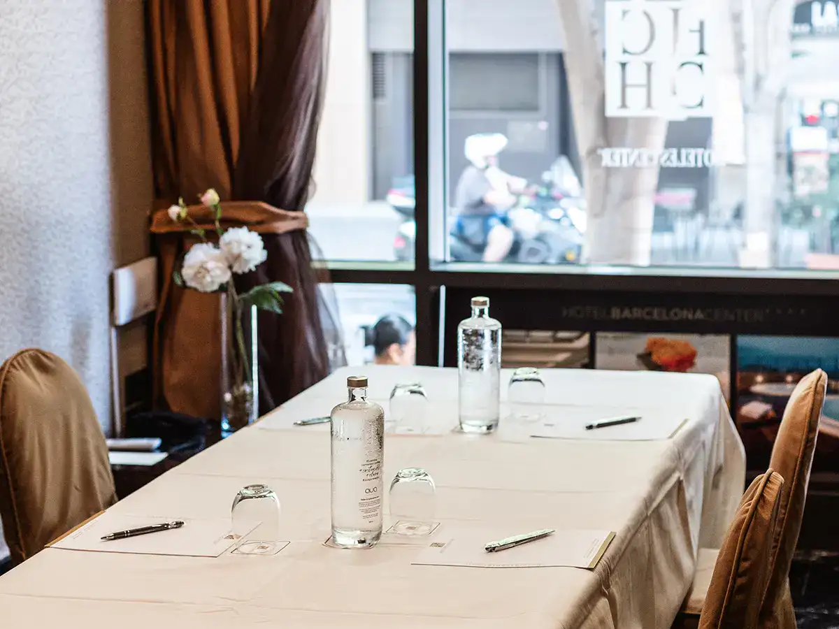Mesa de reuni&oacute;n con botellas de agua y bol&iacute;grafos en un hotel.