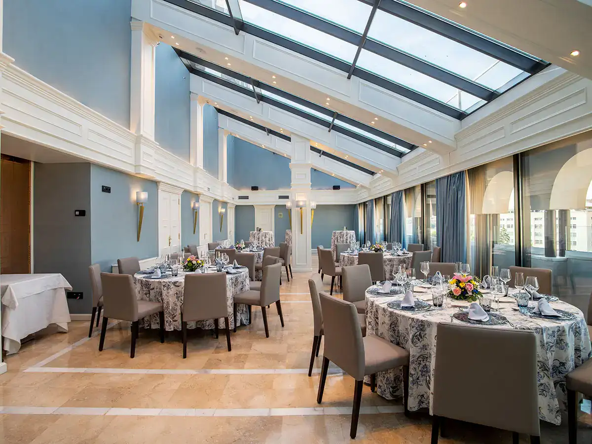 Sal&oacute;n elegante con mesas redondas decoradas para eventos.