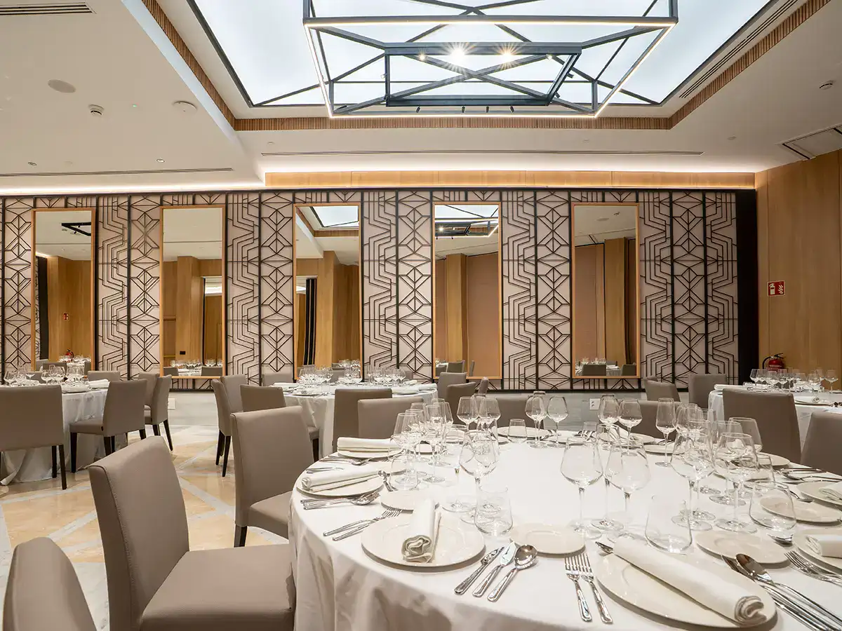 Sal&oacute;n de banquetes elegante con mesas redondas y vajilla lista para evento.