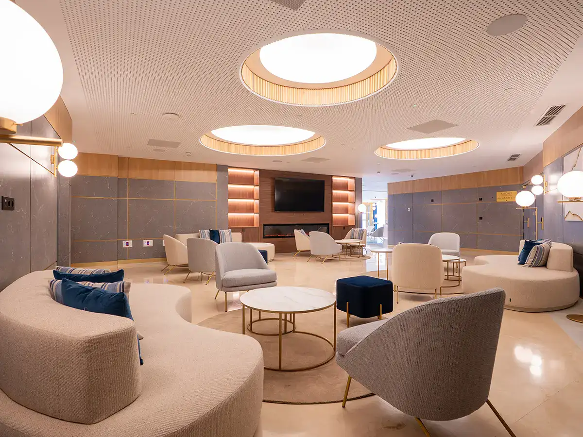 Sala moderna con sof&aacute;s elegantes y luces circulares en el techo.