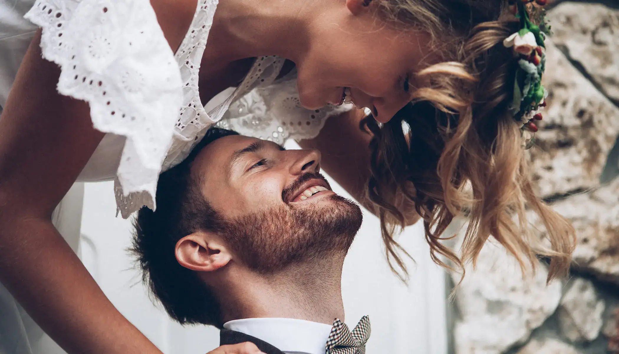 Pareja sonriendo y mirando con ternura bajo un vestido blanco.