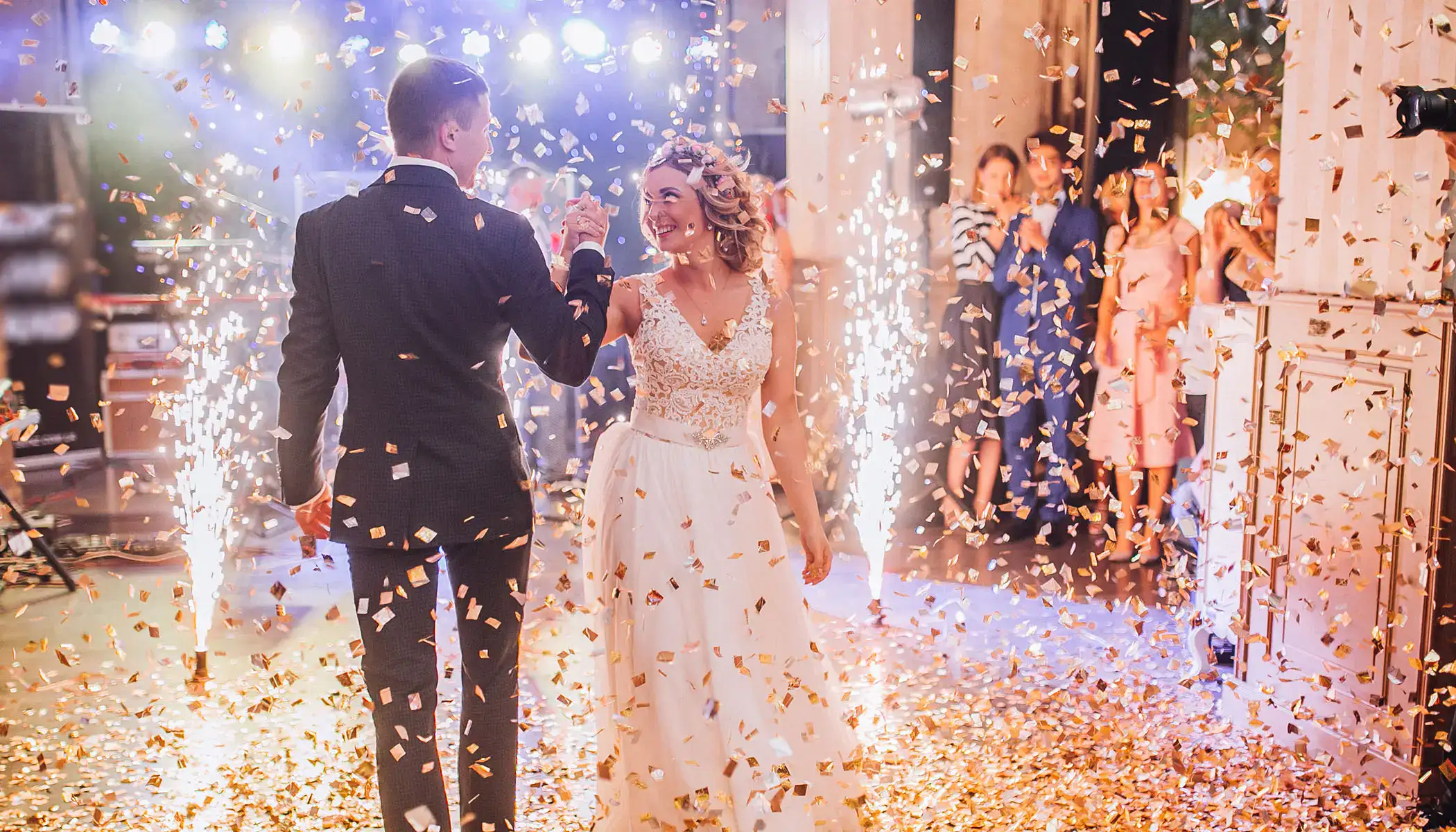 Pareja bailando en su boda con confeti y luces brillantes alrededor.