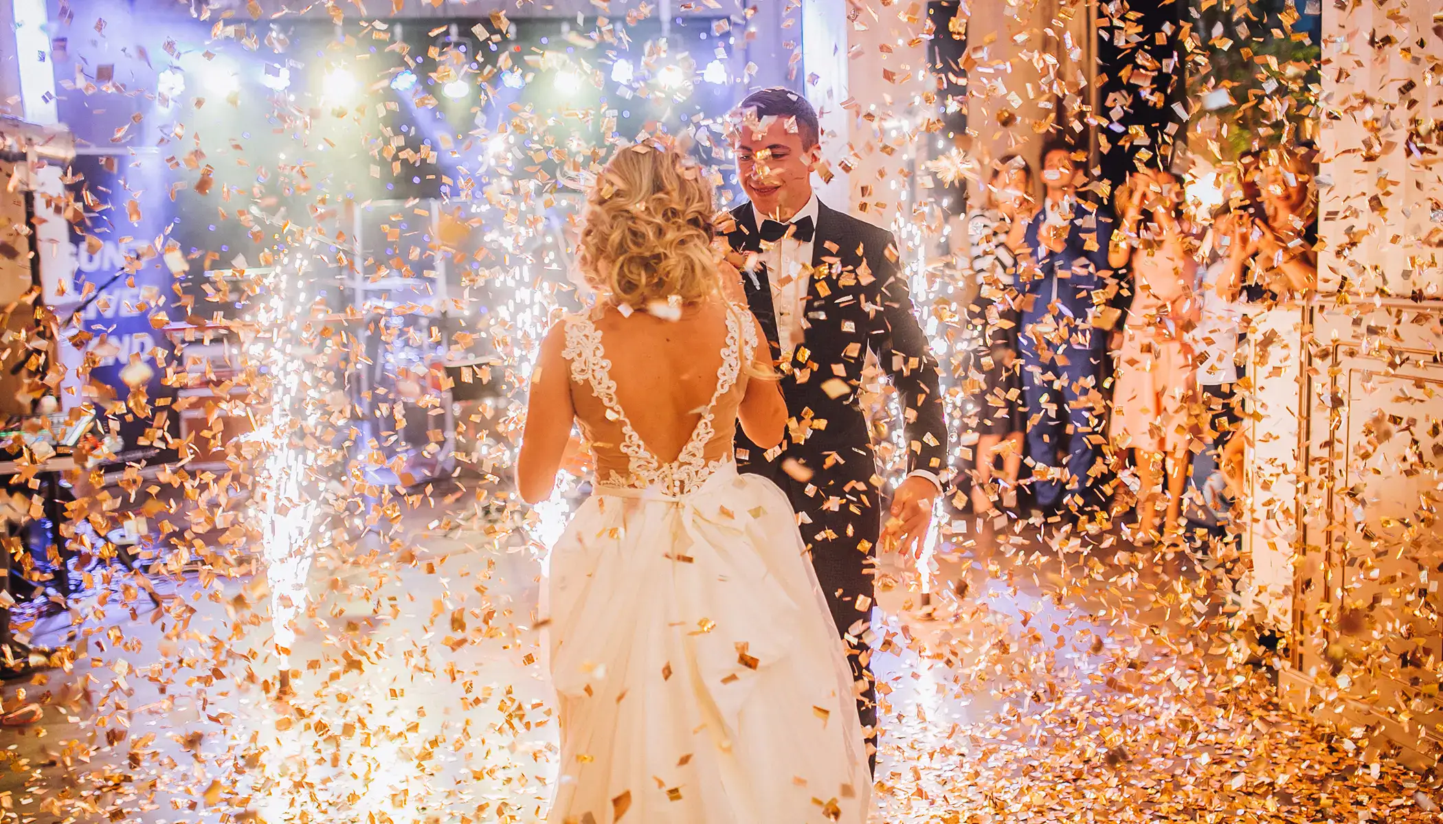 Pareja bailando rodeada de confeti dorado en una celebraci&oacute;n colorida.