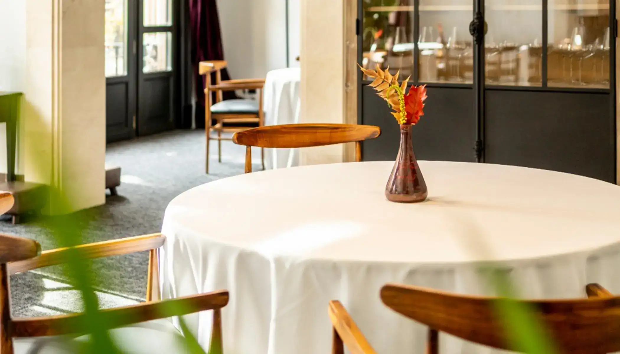 Mesa con mantel blanco y florero marr&oacute;n en restaurante.