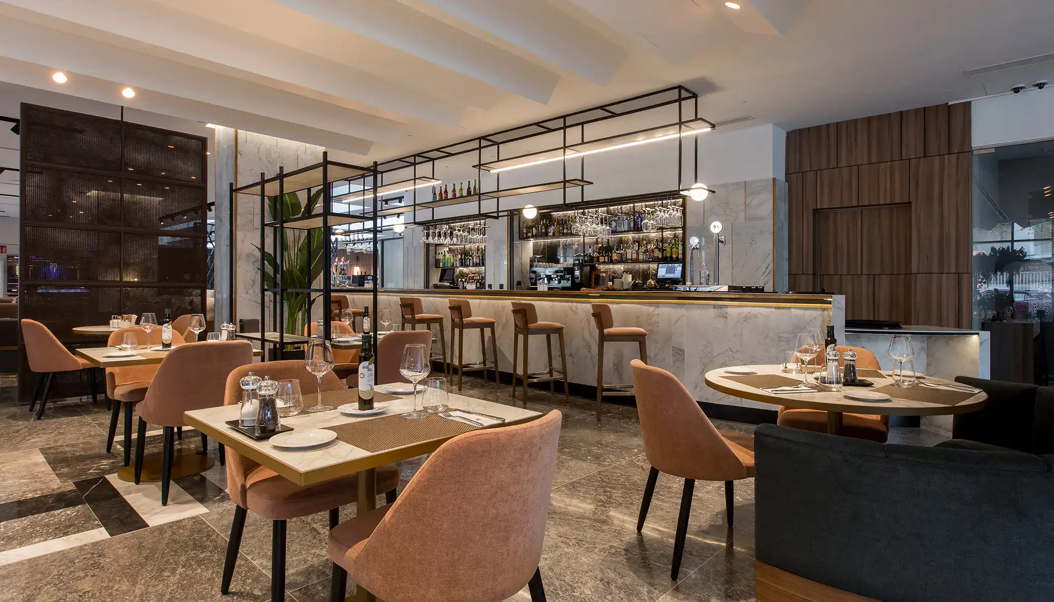 Restaurante moderno con sillas rosas y barra de bar iluminada.