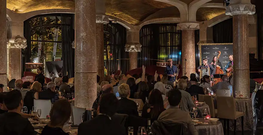 Evento de jazz en restaurante elegante con p&uacute;blico atento y m&uacute;sicos tocando.