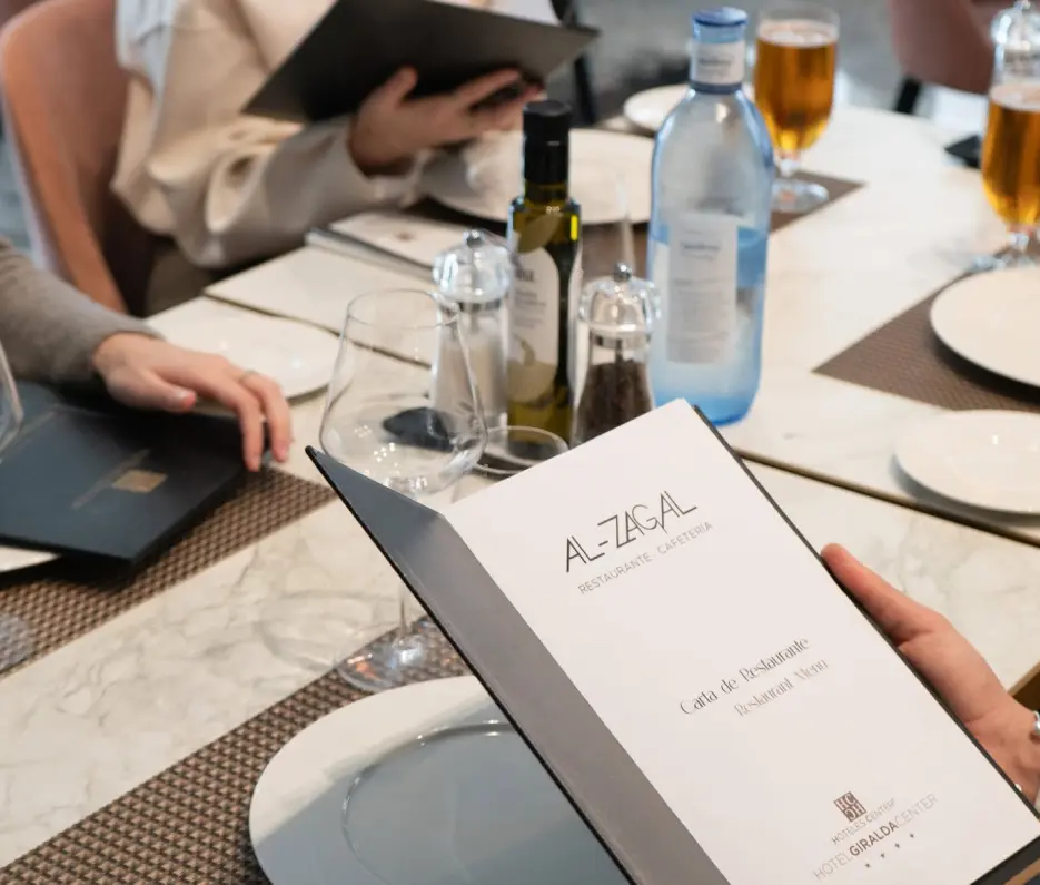 Persona leyendo un men&uacute; en un restaurante elegante con bebidas en la mesa.