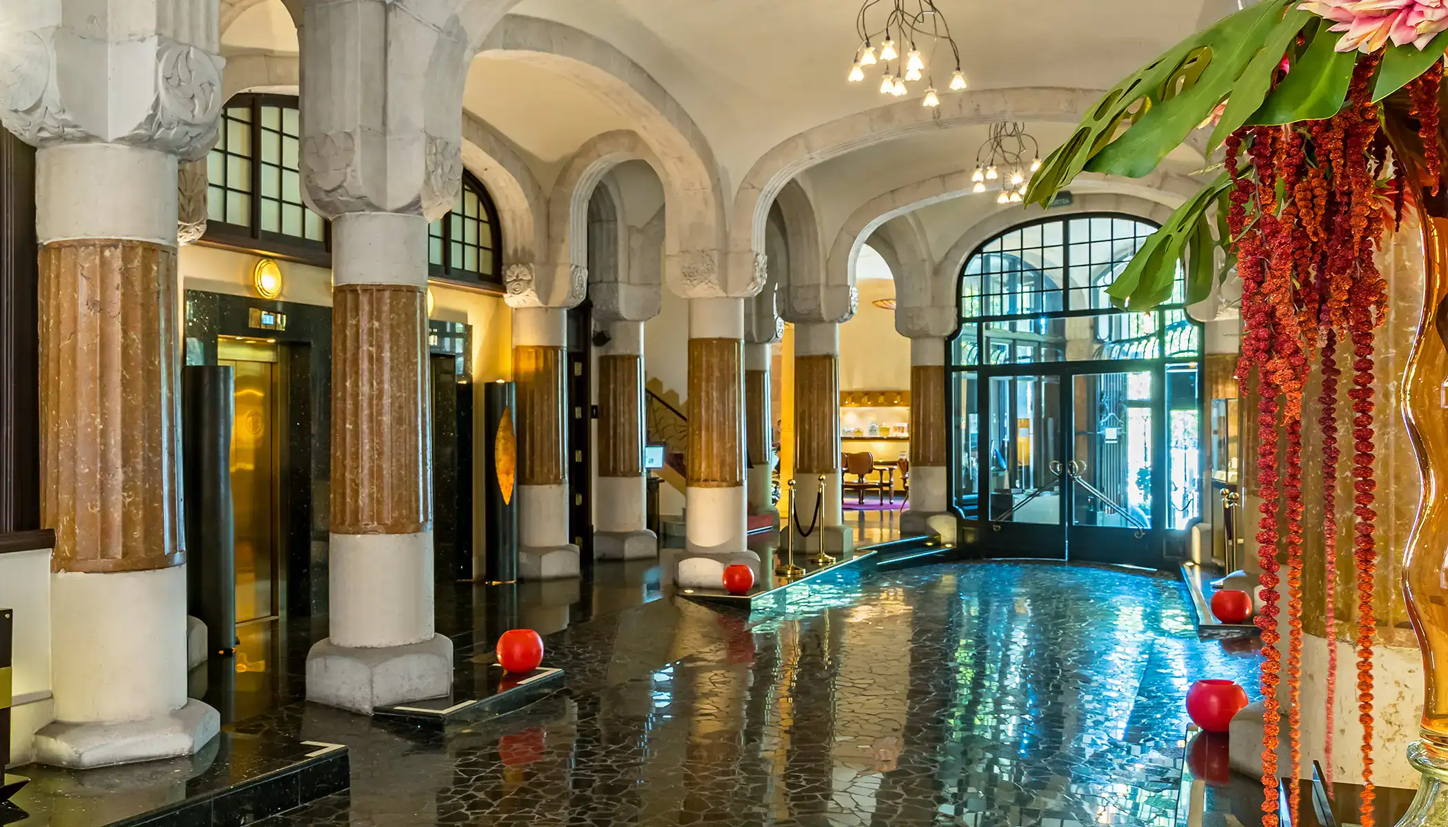 Vest&iacute;bulo elegante con columnas, luces y una moderna entrada acristalada.