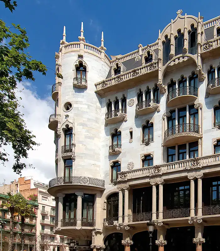 Edificio modernista con balcones elaborados y torres, cielo azul al fondo.
