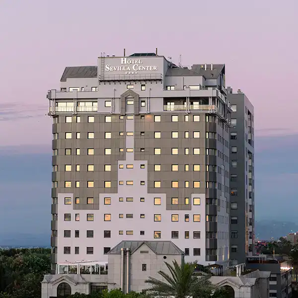 Edificio alto con cartel "Hotel Sevilla Center" al atardecer.