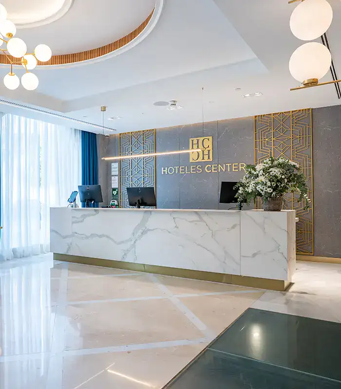 Recepci&oacute;n moderna de un hotel con mostrador de m&aacute;rmol y decoraci&oacute;n floral.
