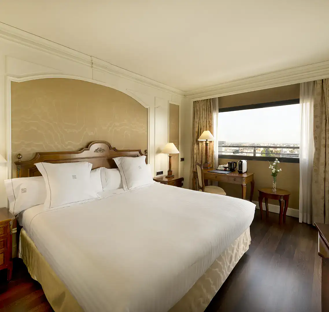 Habitaci&oacute;n de hotel elegante con cama grande y ventana con vista.