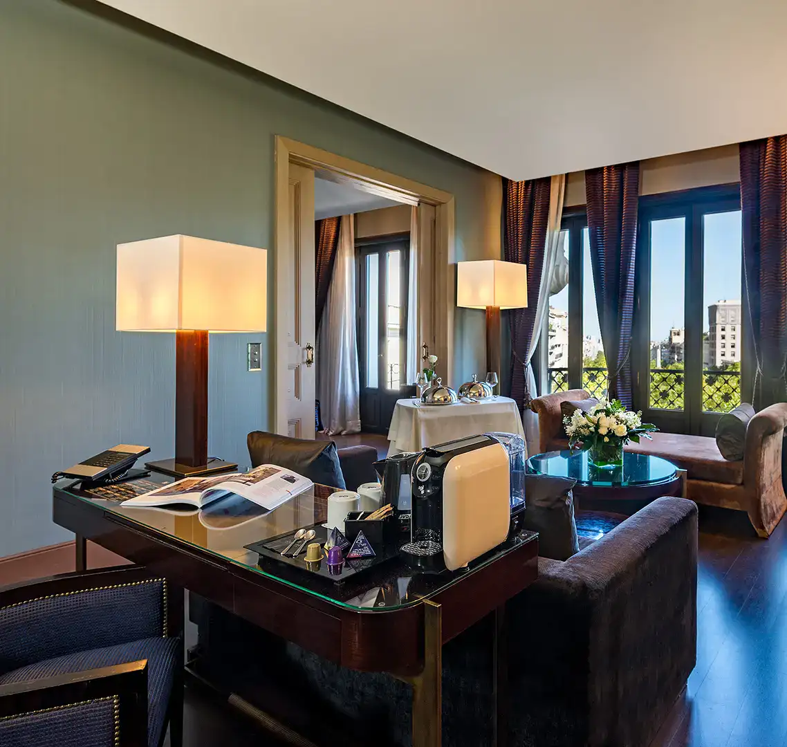 Sala de estar elegante con vista a la ciudad, l&aacute;mparas y cafetera en la mesa.