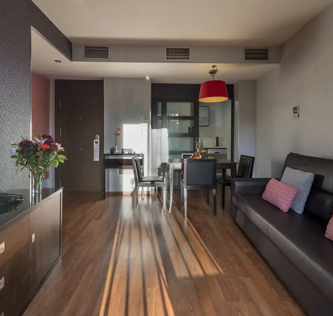 Sala moderna con sof&aacute;, mesa de comedor y flores en la mesa auxiliar.