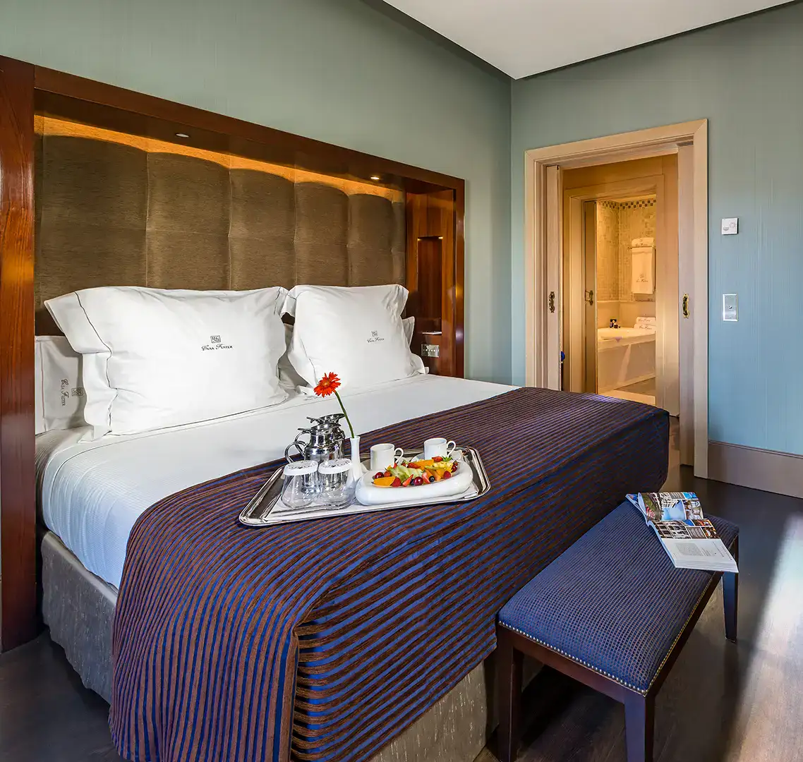 Habitaci&oacute;n con cama doble, desayuno en bandeja y puerta hacia el ba&ntilde;o.