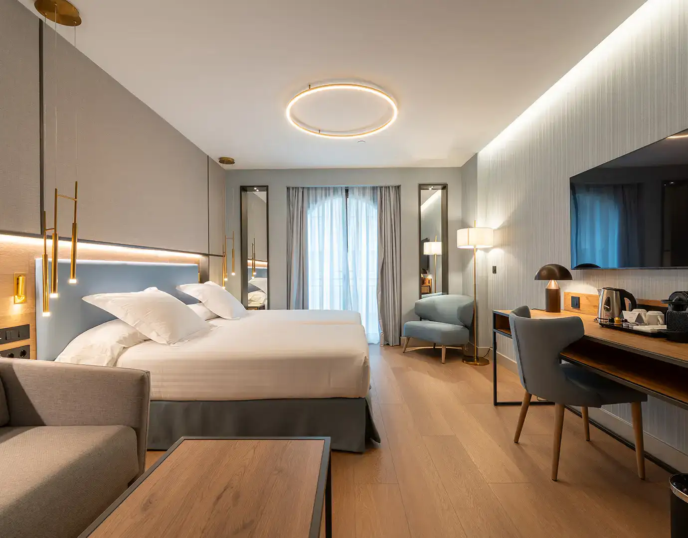 Habitaci&oacute;n moderna de hotel con cama doble, escritorio y sill&oacute;n.