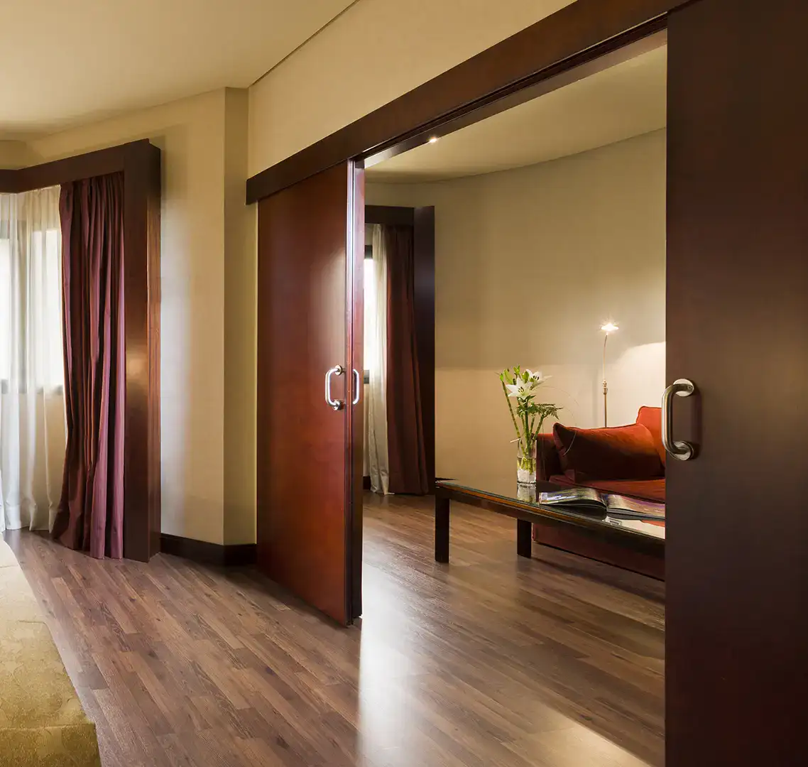 Sala de estar con sof&aacute;, mesa de centro y puertas corredizas de madera.