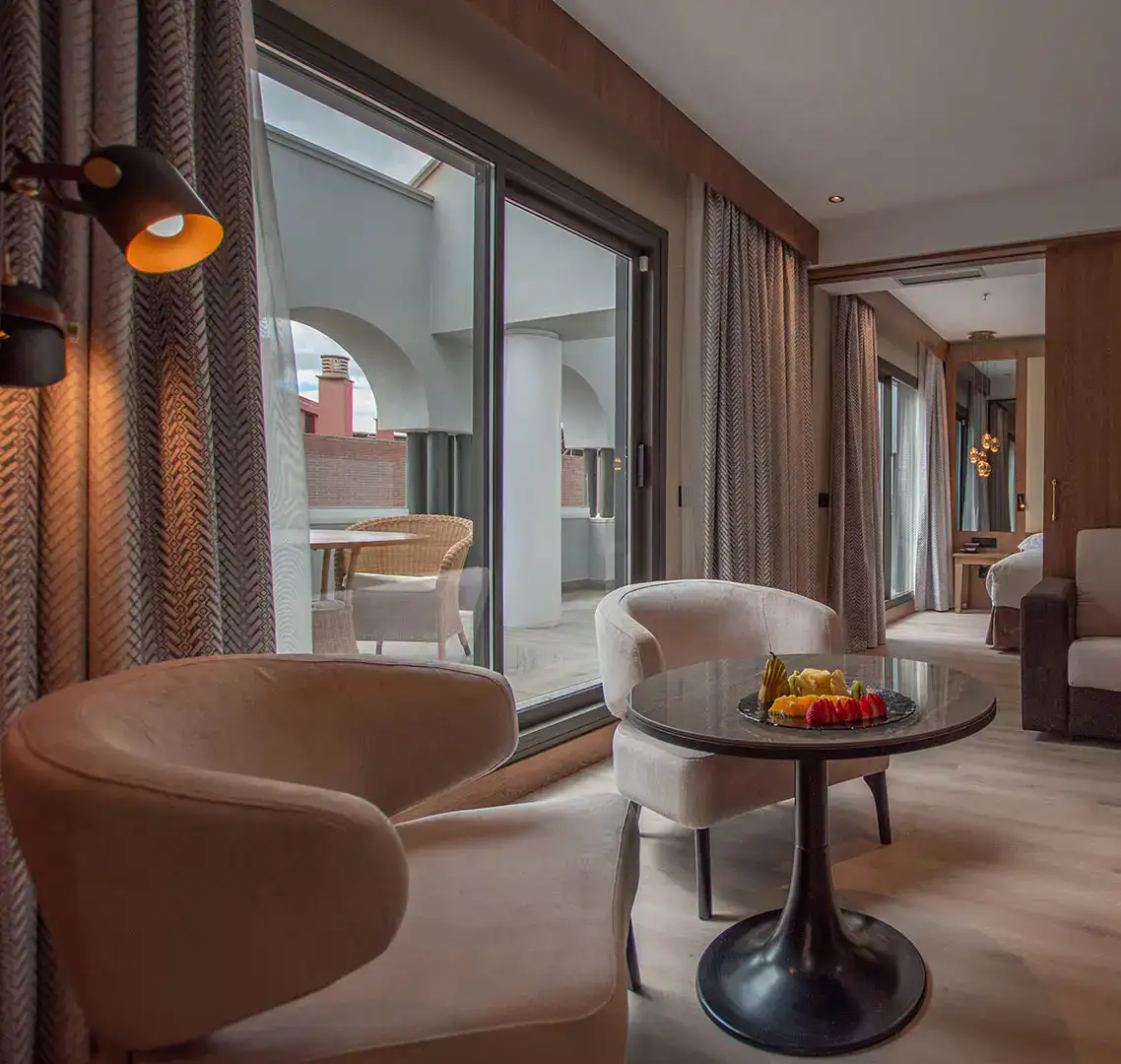 Sala moderna con sillas y mesa, vista a terraza con silla de mimbre.