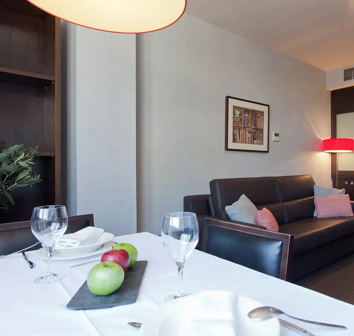 Sala moderna con mesa, sof&aacute; y l&aacute;mpara roja.