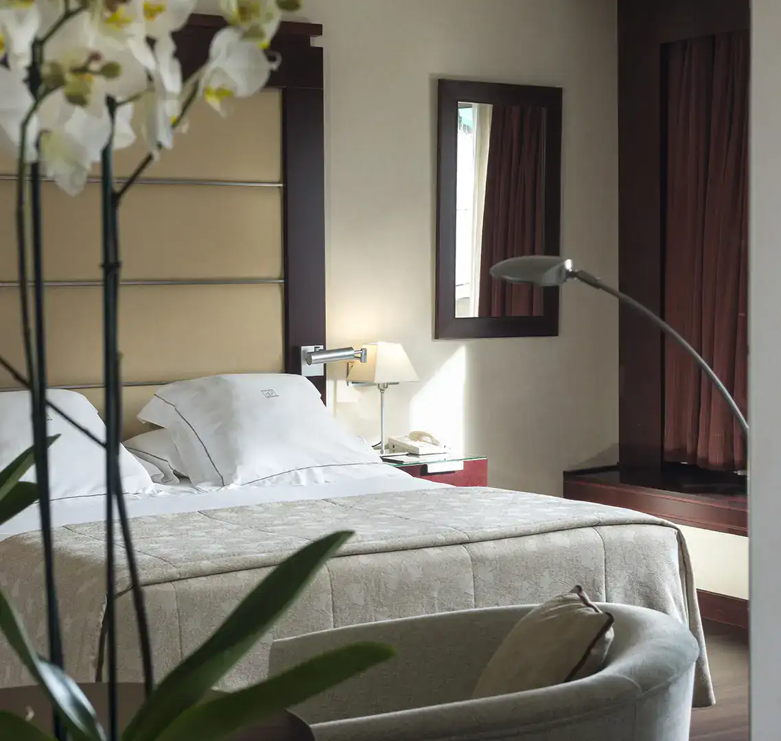 Habitaci&oacute;n elegante con cama, sof&aacute; y l&aacute;mpara moderna.