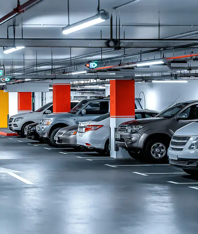 Estacionamiento subterr&aacute;neo con varios autos estacionados en fila.