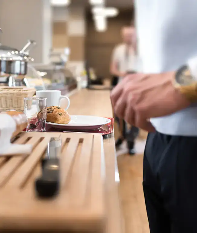 Persona tomando caf&eacute; en una barra, con taza y panecillo.
