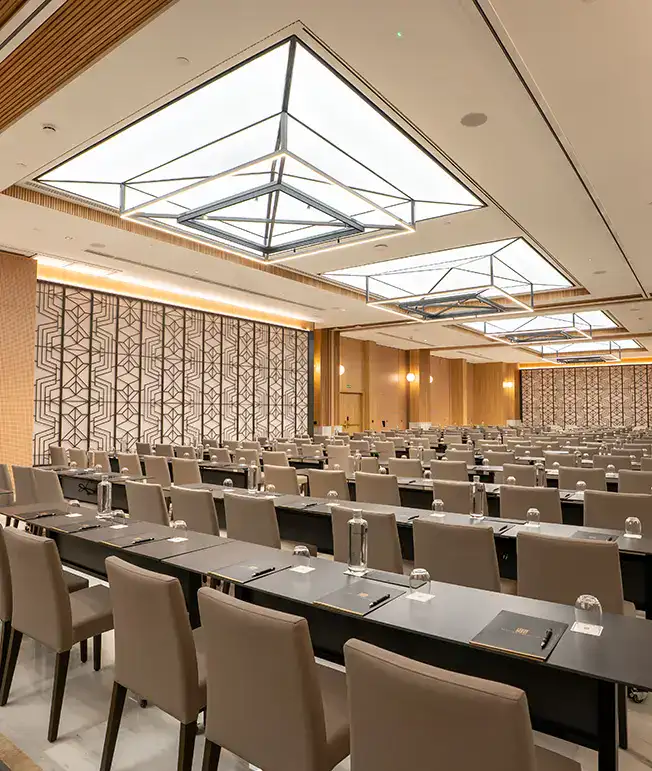 Sala de conferencias moderna con mesas y sillas organizadas en filas.