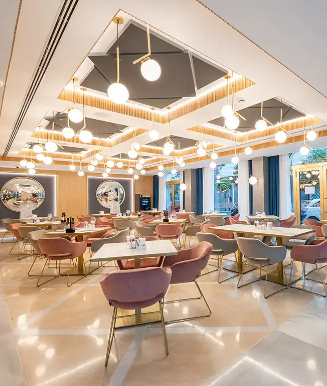 Restaurante moderno con dise&ntilde;o luminoso y sillas rosadas elegantes.