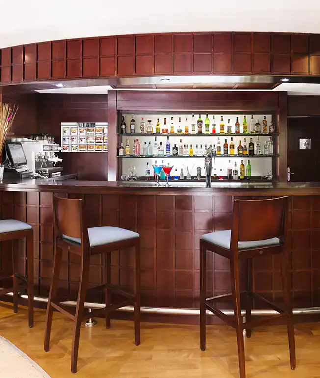 Bar con estantes de licor, sillas altas y m&aacute;quina de caf&eacute;.