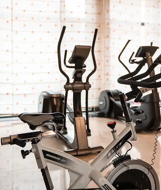 Bicicletas est&aacute;ticas y m&aacute;quinas el&iacute;pticas en un gimnasio.