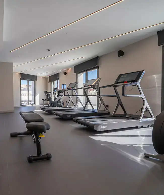 Gimnasio moderno con cintas de correr y ventanas grandes.