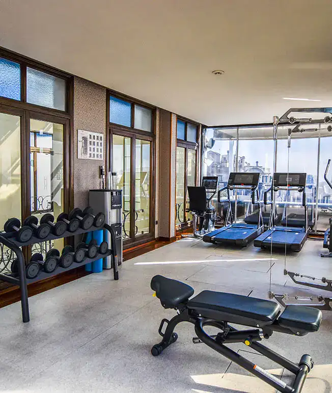 Gimnasio con m&aacute;quinas, pesas y bancos en una sala bien iluminada.