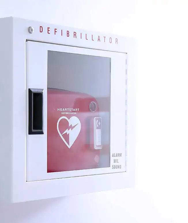 Gabinete de desfibrilador blanco con una caja roja y un &iacute;cono de coraz&oacute;n.