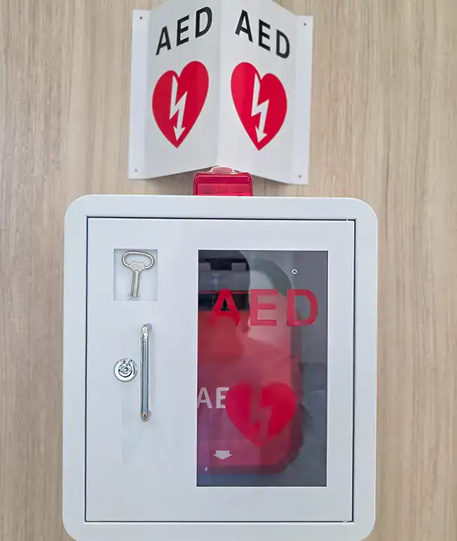 Gabinete con desfibrilador externo automatizado (AED) en la pared.